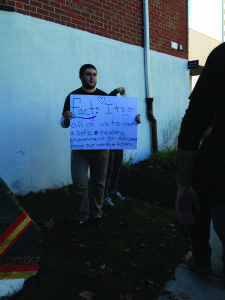 Jospeh Moore-Costa, a brother of Kappa Gamma Rho holds a sign with a fact about sexual assault along the walk (Photo by Samantha Reposa/Charger Bulletin photo)